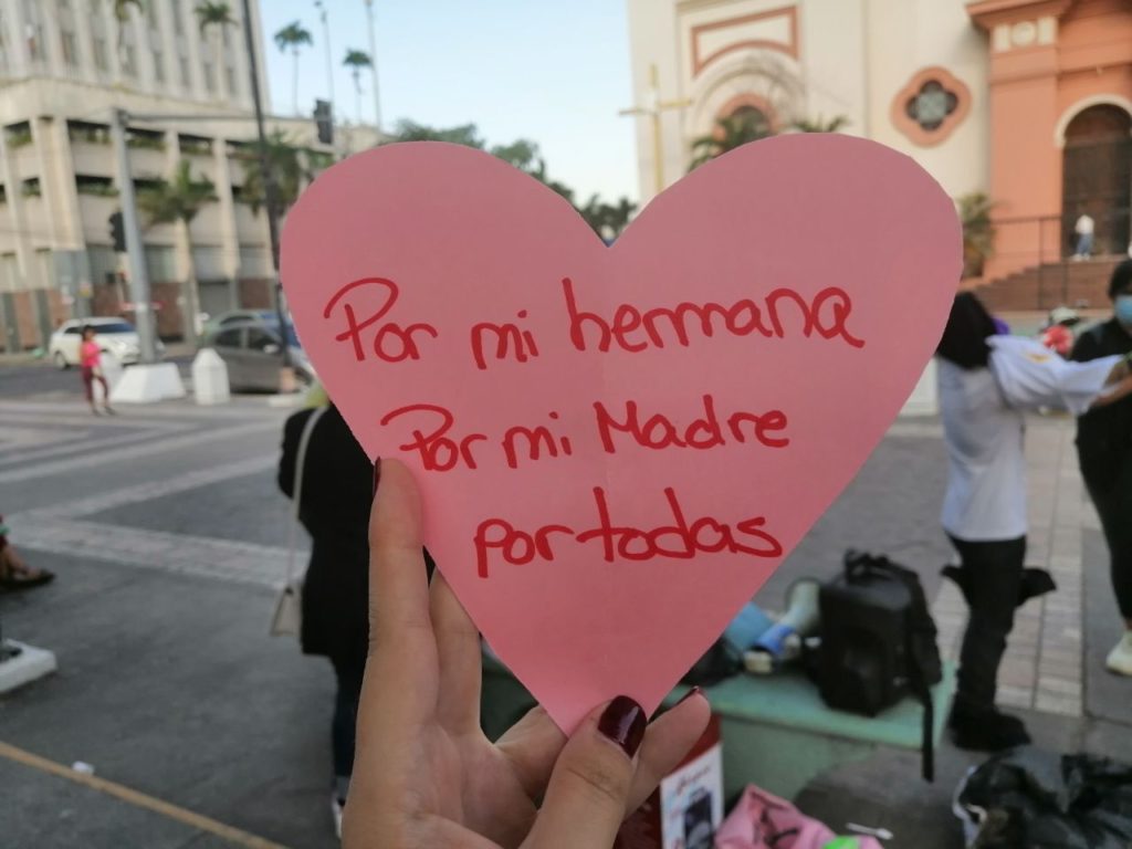 Corazón rosado con escritura en el centro que dice "Por mi hermana, por mi madre, por todas"